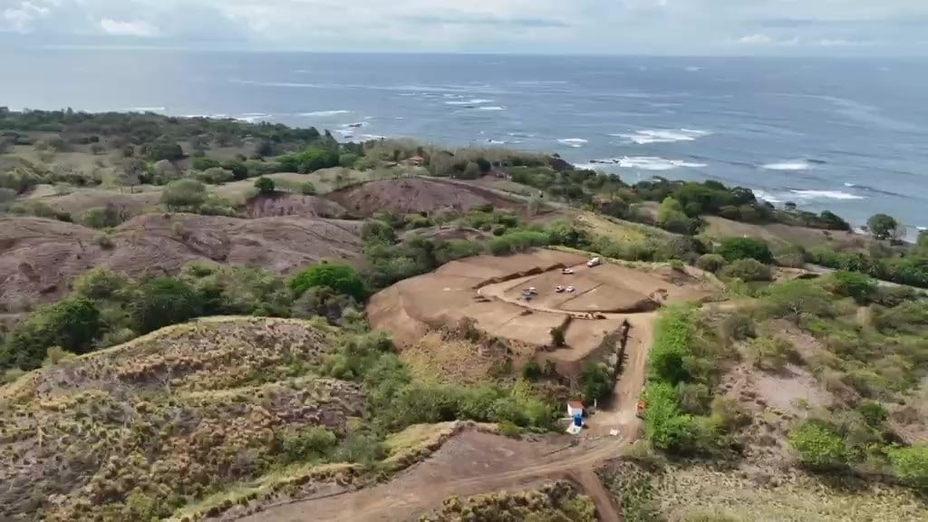 Aerial view of a graded platform and its road on the hill above the sea
