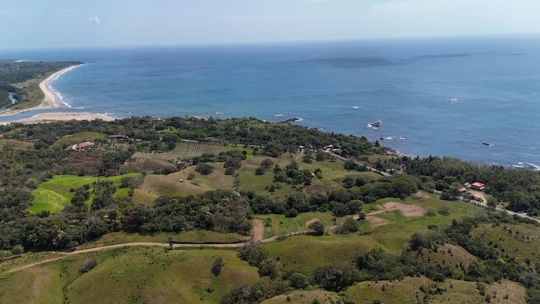 Aerial view of the El Ciruelo coastline with green hills meeting the Pacific
